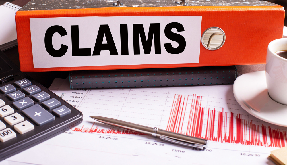 Insurance claims folder on desk with calculator, charts, and coffee cup in law office. Insurance claims folder on desk with calculator, charts, and coffee cup in law office.