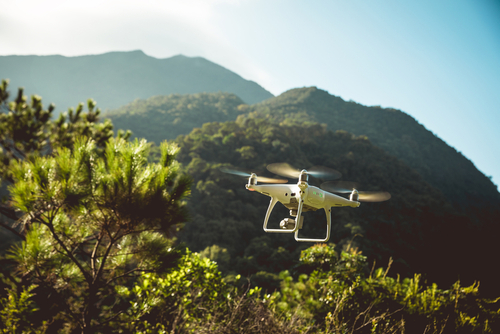 Drone flying over a forested mountain landscape, representing technology used for wildfire evidence collection