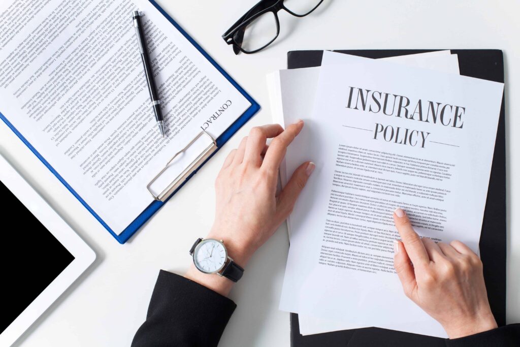 Person reviewing insurance policy and contract documents on desk in law office. Person reviewing insurance policy and contract documents on desk in law office.